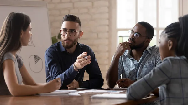 Geconcentreerde jonge zakenpartners met gemengde rassen bespreken ontwikkelingsstrategie. — Stockfoto