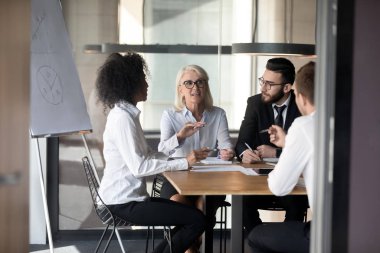 Çok ırklı çeşitli meslektaşlar ofis toplantısında beyin fırtınası hakkında konuştu