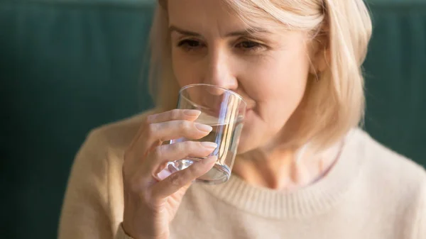 Крупный план пожилой женщины, пьющей тихую воду — стоковое фото