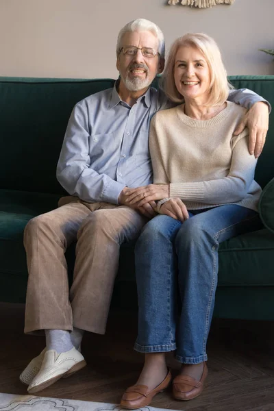 坐在沙发上的一对垂直于上的老夫妇拥抱 — 图库照片