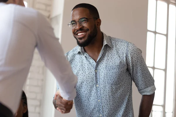 Joyful african american millennial worker shaking hands with colleague. — Stock Photo, Image