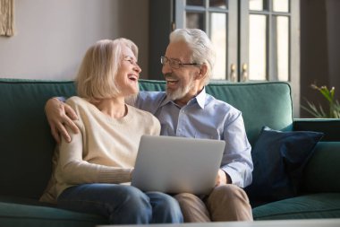 Gülen yaşlı çift dizüstü bilgisayarda komedi izlerken eğleniyor.