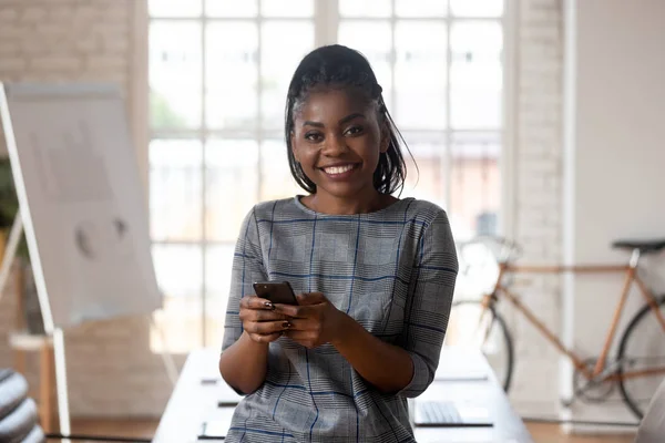 Mixed race smiling female office manager holding smartphone. — Stock Photo, Image