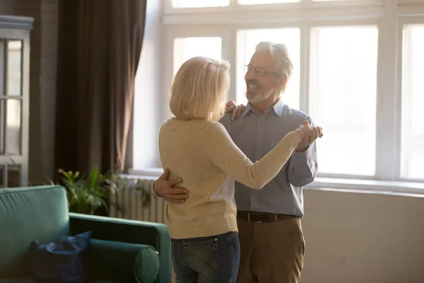 Actieve oudere vrouw en echtgenoot dansen thuis — Stockfoto