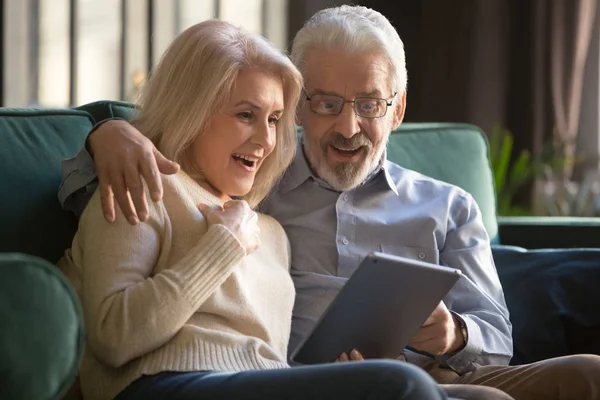 快乐而惊奇的一对老夫妇看着数码平板电脑屏幕 — 图库照片