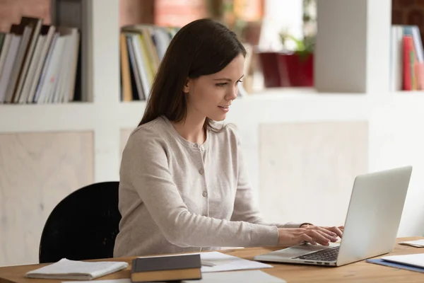 Heureuse étudiante caucasienne concentrée travaillant sur un projet scolaire . — Photo