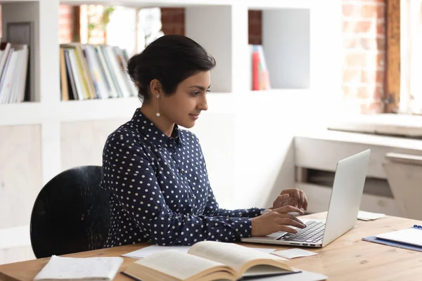 Focado confiante indiano estudante do sexo feminino estudando com livros e computador . — Fotografia de Stock
