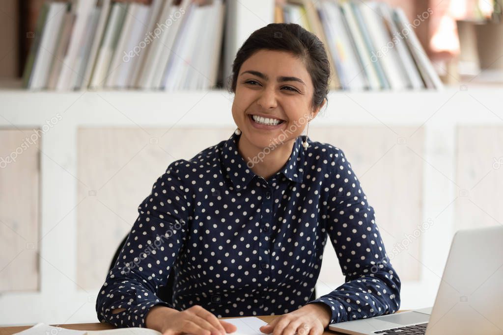 Cheerful positive indian female student talking with somebody aside.