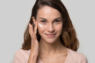 Kozmetik krem süren güzel bir kadının portresi.