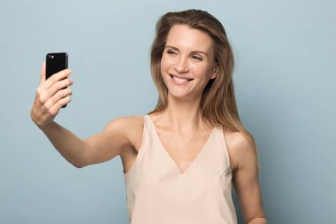 Gülümseyen çekici kadın selfie çekiyor, cep telefonu kullanıyor.