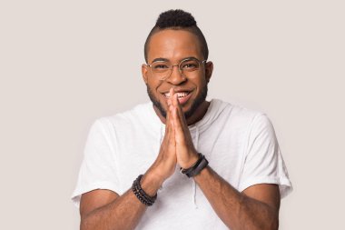 Gülümseyen Afrikalı Amerikalı adam beklenti ve beklenti içinde el ele tutuşuyor.