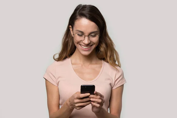 Mujer joven feliz satisfecho con gafas mirando a la pantalla del teléfono — Foto de Stock