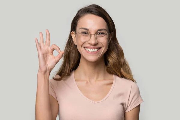 Excited satisfied young woman wearing glasses showing ok gesture — Stock Photo, Image
