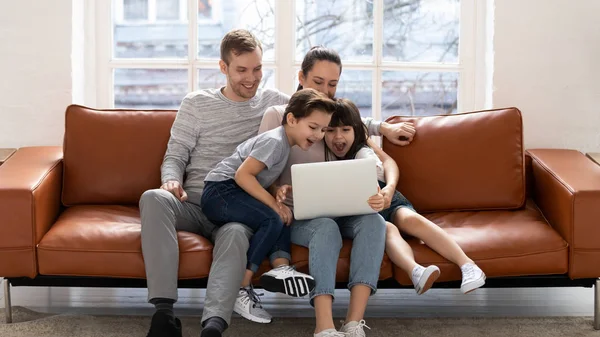 Счастливая молодая семья с детьми развлекается с помощью ноутбука — стоковое фото