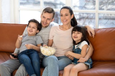 Çocuklu mutlu bir aile patlamış mısır yiyor.