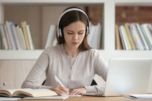 Soustředěná studentka studuje, nosí bezdrátová sluchátka. — Stock fotografie