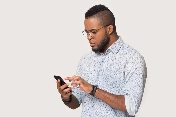 Homem afro-americano sério usando telefone isolado em fundo branco — Fotografia de Stock