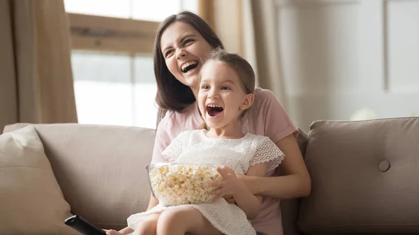 Sonriente mamá y su hija pequeña ver película comer palomitas de maíz —  Fotos de Stock