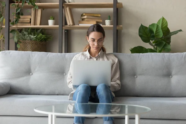 Millennial kvinna sitta på soffan hemma med laptop — Stockfoto