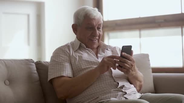 Hombre mayor feliz celebración de teléfono inteligente utilizando aplicaciones móviles en línea — Vídeos de Stock