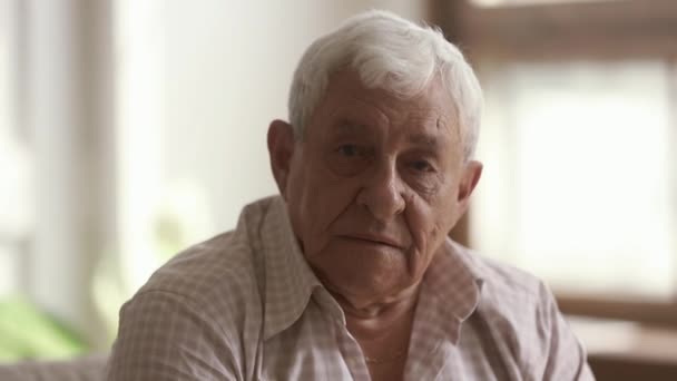 Senior old gray-haired man looking at camera, close up portrait — Stock Video