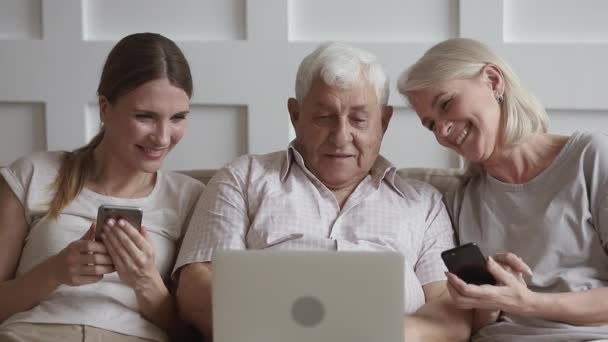 Felice vecchi genitori e giovane figlia utilizzando dispositivi che parlano ridendo — Video Stock
