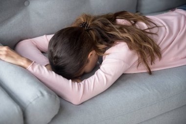 Evdeki kanepede yatan üzgün kız motivasyondan yoksun.