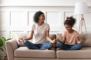 Afrikalı anne kız kanepeye oturup kahkaha atarak meditasyondan uzak duruyor.