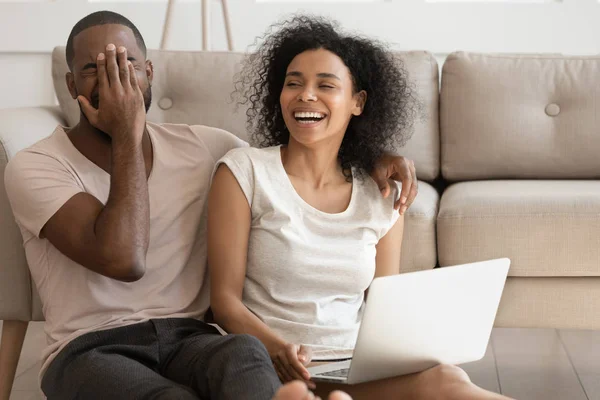 Sonriendo pareja afroamericana se ríen viendo divertido vídeo en el ordenador portátil —  Fotos de Stock