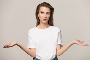 Kararsız bir kadın omuz silkiyor, kafası karışık, kameraya bakıyor.