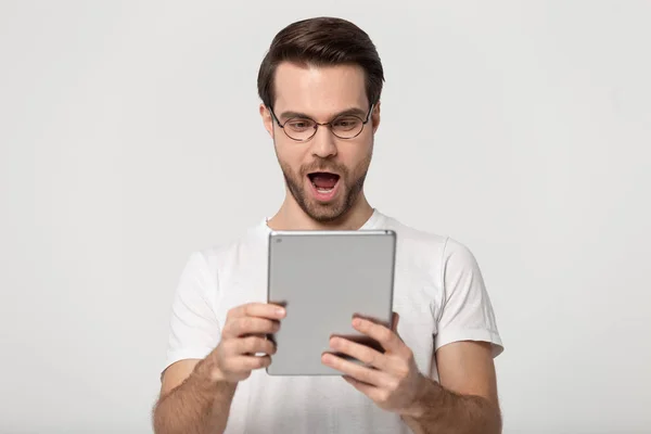 안경을 쓴 흥분 한 백인 남자는 태블릿을 사용하면 충격을 받는다 — 스톡 사진