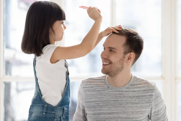 Ragazzina che gioca con papà facendo acconciatura — Foto Stock