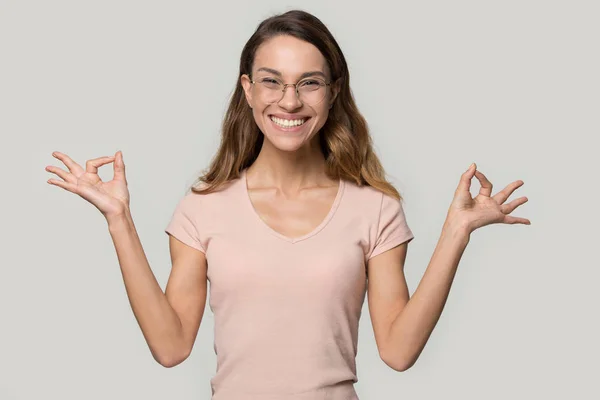 Mosolygó elégedett fiatal nő visel szemüveg meditálás, gyakorló jóga — Stock Fotó