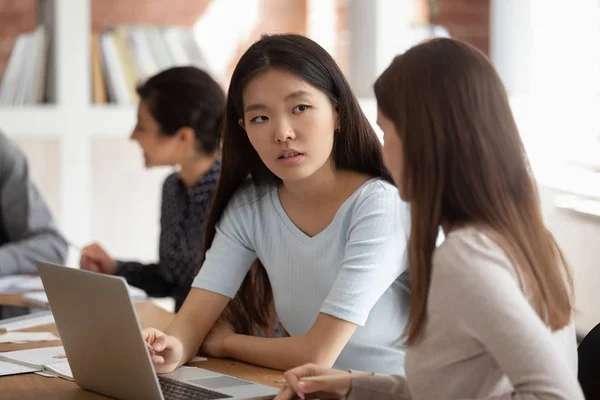 Concentrado asiático estudante feminino ouvindo companheiro de equipe novo tema explicação . — Fotografia de Stock