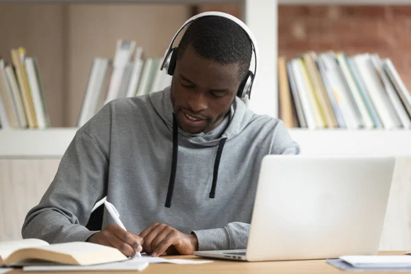 Estudante negro focado usando fones de ouvido bluetooth, ocupado com estudo , — Fotografia de Stock