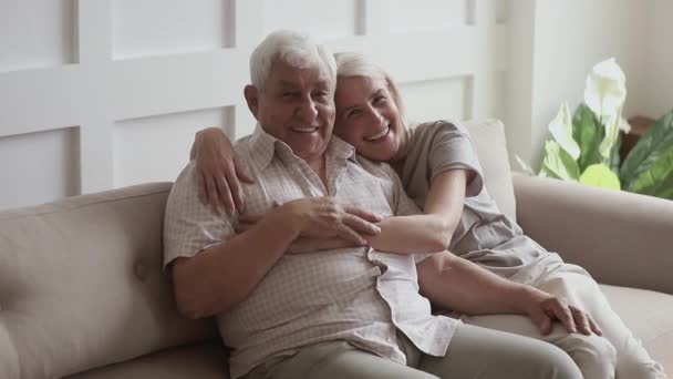 Счастливая старшая семья пара сидеть на диване дома, портрет — стоковое видео