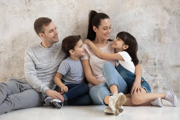 Gelukkig gezin met kleine kinderen zitten op de vloer knuffelen — Stockfoto