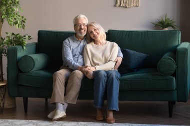 Kanepeye oturup kameraya poz veren olgun bir çift.