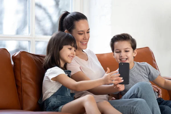 幸せな若いお母さんと子供たちは無線インターネットでスマートフォンを使用して — ストック写真
