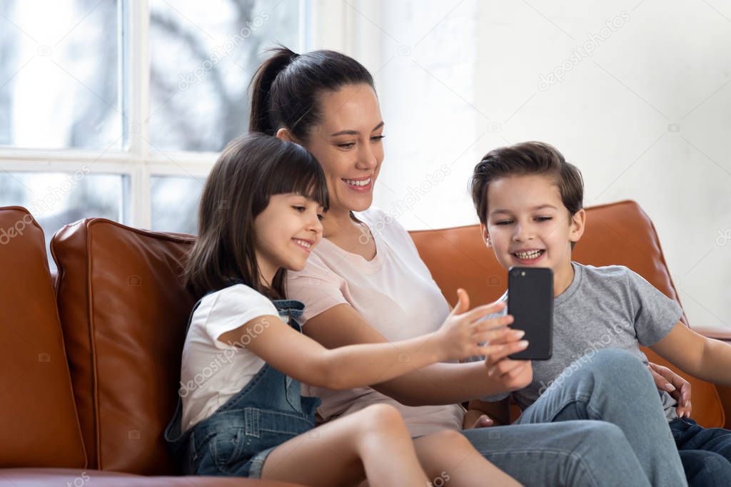 Happy young mom and kids using smartphone with wireless internet