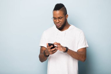 Mutlu Afrikalı Amerikalı adam telefonu kullanıyor, ekrana bakıyor.