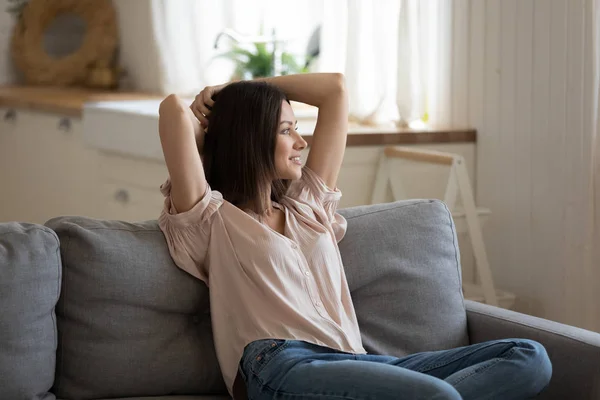 Расслабленная ленивая леди, держащая руки за головой гостиной на диване — стоковое фото