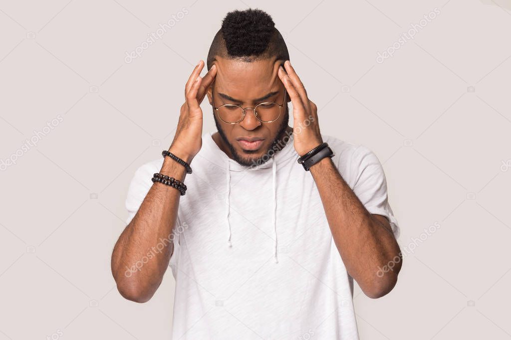 Upset African American man massaging temples, suffering from headache