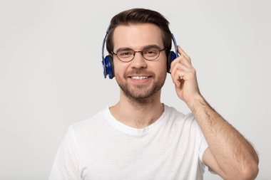 Gülümseyen milenyum çocuğu Bluetooth kulaklıklarıyla müziğin tadını çıkarıyor.