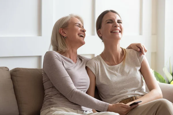 Overjoyed mulher de meia-idade rindo de vídeo engraçado com a filha . — Fotografia de Stock