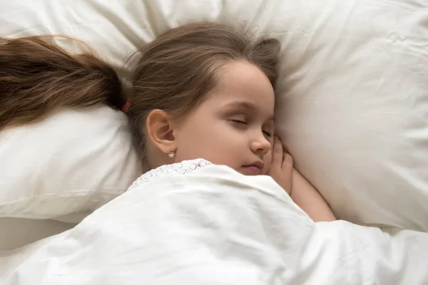 Pequeña niña tranquila durmiendo en la acogedora cama blanca — Foto de Stock