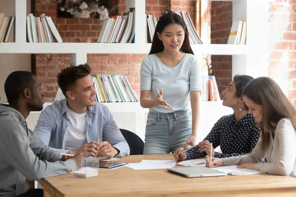Smiling asian female team leader holding meeting with diverse groupmates. — Stock Photo, Image