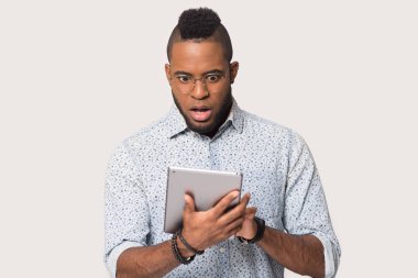 Şaşırmış Afrikalı Amerikalı bir adam açık ağızla tablete bakıyor.