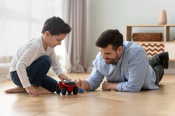 Father and little son playing toy cars on warm floor — Stock Photo, Image