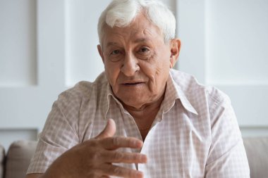 Mutlu büyükbaba kameraya bakıyor, yetişkin çocuklarla konuşuyor..